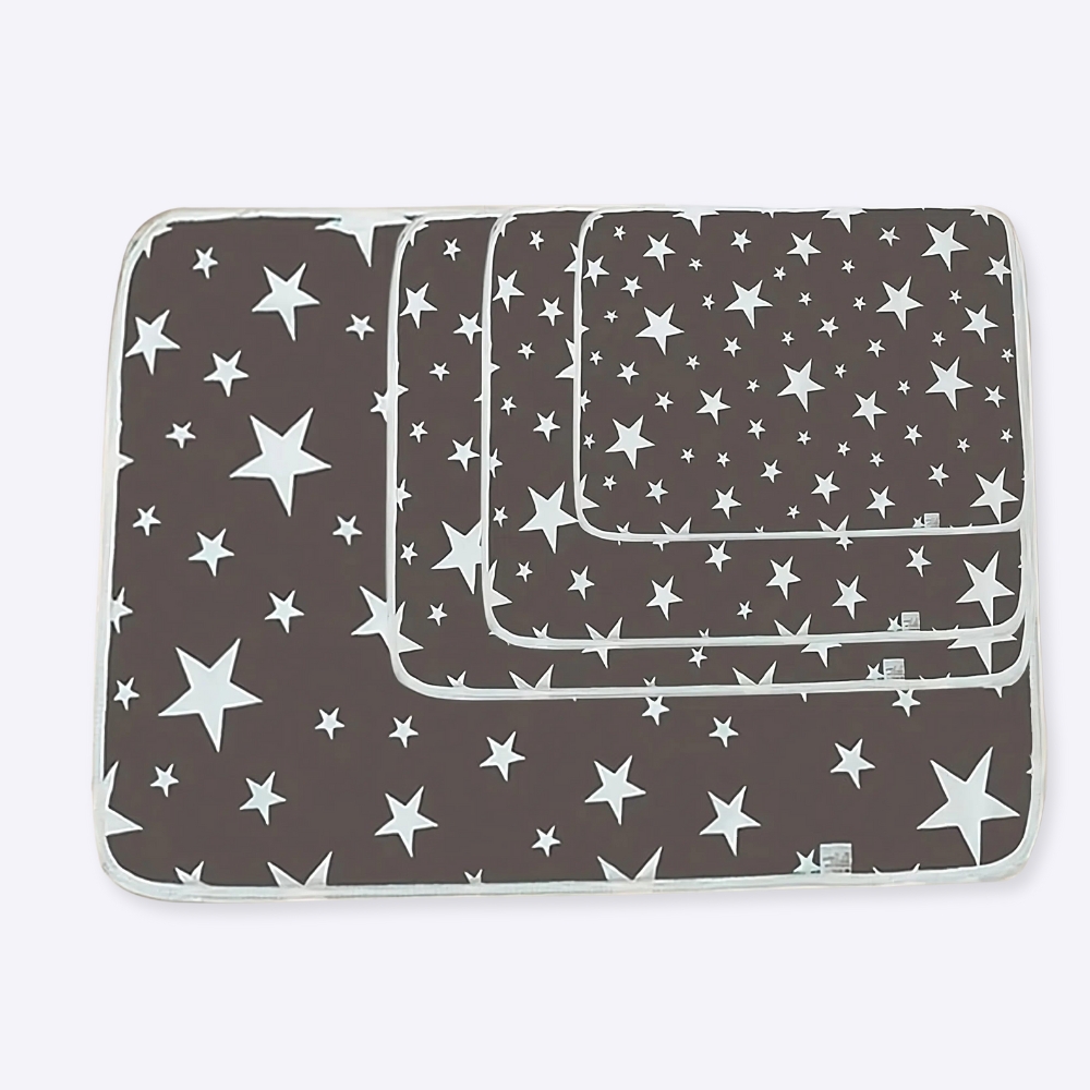 Tapis de propreté gris avec des étoiles blanches, lavable et réutilisable pour chien, avec ' taille différente, les modèles sont empilés les uns sur les autres, posés au sol, et juste à coté se trouve un petit cadre blanc.