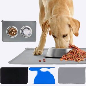 Labrador en train de manger dans sa gamelle en inox, des croquettes débordent, la gamelle est posé sur un tapis gris , et à gauche du chien on voit un tapis gris avec 2 gamelles posées dessus