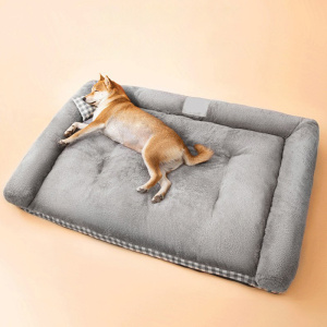 Un chien est installé en train de dormi sur un lit/canapé pour chien molletonné, gris, il est présenté sur un fond orange
