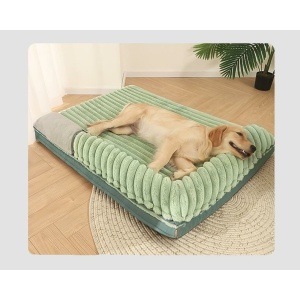 grand chien allongé sur un lit pour chien vert , doux, avec un coussin intégré en angle