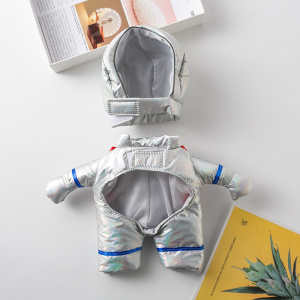 déguisement pour chien de cosmonaute gris, installé à plat sur un bureau près d'un livre jaune et d'une plante