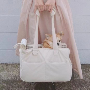 sac de transport pour chien blanc, pratique et confortable, tenu par une femme dont on ne voit pas le haut du corps, avec un petit chien installé dedans