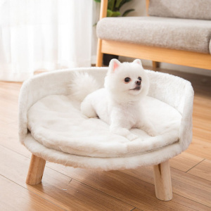 petit chien blanc, de trouve sur un canapé pour chien blanc , tout doux, et rond, monté sur pieds en bois